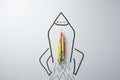 Creative idea and business startup concept with colorful pencils on the rocket drawn on white wall background.