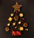 Creative idea Christmas or New Year tree made of gold and red balls, stars, gift boxes, drums and fir cones on a black background Royalty Free Stock Photo