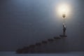 Creative and idea concept with front view on man in suit on the top of stairway turning on big light bulb on dark concrete Royalty Free Stock Photo