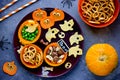 Creative idea for Halloween snack - skull bone dry cereal, cheese ghosts, carrot pumpkin with eyes, cookie and vegetables on plate
