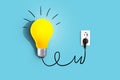 Creative idea, a yellow light bulb is plugged into a socket and glows on a blue background. Business and education. Brainstorm, Royalty Free Stock Photo