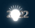 Creative ideas coming up in the year 2022, bright light bulb representing good idea, on dark blue background and 3D embossed