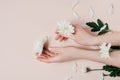 Creative image beautiful groomed woman`s hands with white flowers with copy space on pink background in minimalist style. Concept