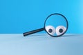 Creative image of a magnifying glass with eyes on a blue background Royalty Free Stock Photo