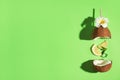 Creative image of summer cocktail made with coconut, lemon slice, mint, ice and straw on green background, top view Royalty Free Stock Photo