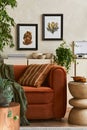 Creative interior composition of living room with designed couch, two mock up poster frames, coffee table, plants, books.