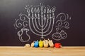 Creative Jewish holiday Hanukkah background with spinning top dreidel over chalkboard with hand drawing Royalty Free Stock Photo