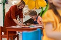 Creative kids during an art class in a daycare center or elementary school classroom drawing with female teacher. Royalty Free Stock Photo