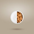 Creative layout of almonds and cream in a round white jar on a beige background.