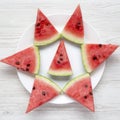 Creative layout of chopped watermelon on white plate over white wooden surface, top view. Flat lay, overhead, from above Royalty Free Stock Photo