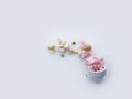 Tiny coffee or tea cup with pink flowers and buds isolated on a light background