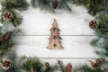 Creative layout frame made of Christmas tree branches and pine cones on white background with figurine of wood Christmas tree