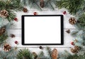 Creative layout frame made of Christmas tree branches, pine cones and tablet pc on white wooden background. Xmas and New Year Royalty Free Stock Photo