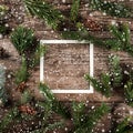Creative layout made of Christmas fir branches with frame of paper card note, pine cones and snowflakes on wooden background Royalty Free Stock Photo