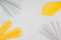 Creative layout made of raw yellow spaghetti pasta and shadows on a grey background. Minimal summer food concept with copy space.