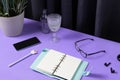 Creative layout with stationery, coffee cup and smartphote on purple table