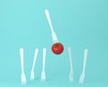 Creative layout of tomato with a fork floating on pastel blue background. minimal idea food concept