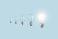 Creative light bulbs loading process and one glowing light bulb on a blue background. Creative idea, concept. Uploading a new idea Royalty Free Stock Photo