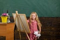 Creative little girl painting on studio easel. Creative artist at work