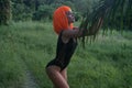 Creative look of woman in orange wig isolated in palm trees forest