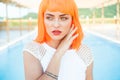 Creative look of woman in orange wig by the pool