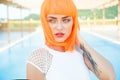 Creative look of woman in orange wig by the pool