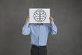 Creative man covers his face with a sheet of paper with a picture of a human brain