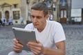 Creative man sitting on sidewalk and using tablet computer Royalty Free Stock Photo