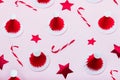 Creative minimal christmas pattern background. Christmas candy canes, red stars and paper santa caps on a pink Royalty Free Stock Photo