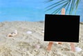 Creative minimal summer idea. Blackboard on sand with blur blue sea and tropical palm leaf. Vacation promotion sale concept. Creat Royalty Free Stock Photo