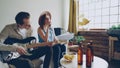 Creative musical duet is practising at home woman is singing in microphone and man is playing the guitar. Young cheerful Royalty Free Stock Photo