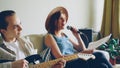 Creative musical duet is practising at home woman is singing in microphone and man is playing the guitar. Young cheerful