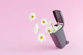 A creative nature concept with white flowers flying out from a trash can against a pastel pink background. Minimal spring and Royalty Free Stock Photo