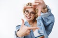 Creative and optimistic joyful charming european woman with blond hair and red lipstick in denim jacket and glasses