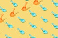 Creative pattern made of blue and orange plastic beach toy shovels isolated on yellow background.