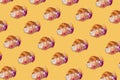 Creative pattern made of freshly baked croissant with flowers on pastel yellow background. Minimal spring or summer concept