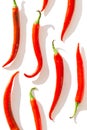 Creative pattern made of red chilli peppers on white sunlit background with shadow. Healthy food ingredient concept. Flat lay. Top