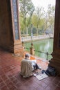 Creative pensive artist painting in colorful Spanish square in Seville, Spain