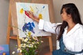 Creative pensive female painter paints a colorful abstract picture. Closeup of painting process in art workshop or home