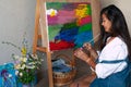 Creative pensive female painter paints a colorful abstract picture. Closeup of painting process in art workshop or home