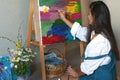 Creative pensive female painter paints a colorful abstract picture. Closeup of painting process in art workshop or home