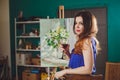 Creative pensive painter girl paints a colorful picture on canvas with oil colors in workshop. Royalty Free Stock Photo