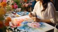 Creative pensive painter paints a colorful picture. Closeup of painting process in art workshop Creative positive woman painter