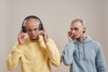 Creative people. Two young twin brothers in casual wear with tattoos and piercings listening music in headphones and Royalty Free Stock Photo