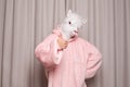 Creative person in pink hoodie with lama head showing thumb up on studio wall background