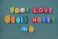 Your love still hurts me, phrase composed with multi colored stone letters over green sand Royalty Free Stock Photo