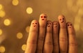 Creative picture of smiley faces drawn on fingers with yellow bokeh lights on the background