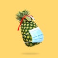 Creative Pineapple in sunglasses and medical mask on a yellow background