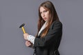 Creative portrait of a businesswoman with a hammer in her hands. Gray background Royalty Free Stock Photo