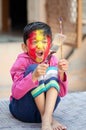 Creative Portrait of cute little Indian Asian Caucasian boy child colored face screaming holding paint brushes in hands Royalty Free Stock Photo